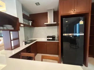 a kitchen with wooden cabinets and a black refrigerator at Phranang Place- SHA Extra in Ao Nang Beach