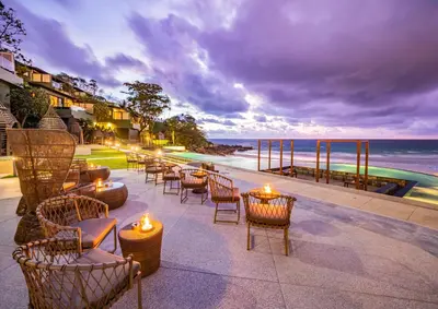 a patio with chairs and tables and a view of the ocean at The Shore At Katathani - Adult Only - SHA Extra Plus in Kata Beach