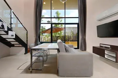 a living room with a couch and a table and a tv at The Aristo by Holy Cow, 4-BR loft, 150 m2, pool view in Surin Beach