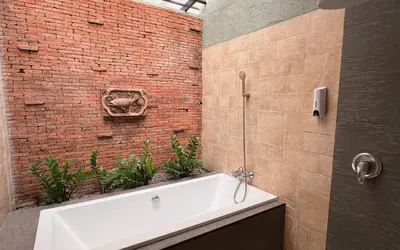 a bathroom with a white bath tub next to a brick wall at Baleeyan in Thalang