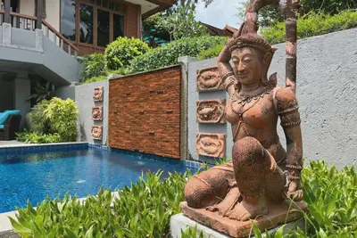 a statue sitting next to a swimming pool at Baleeyan in Thalang