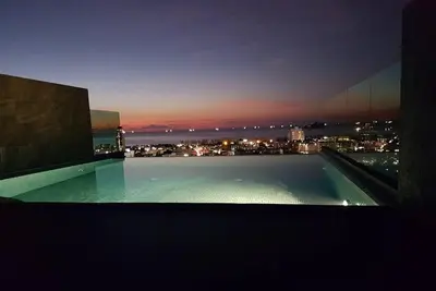 a swimming pool with a view of a city at night at Searocco Phuket in Patong Beach