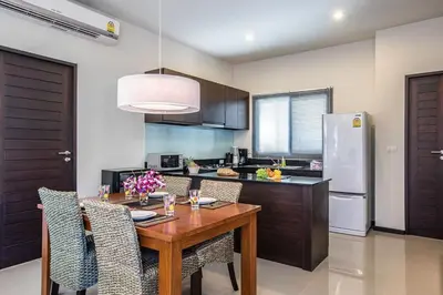 a kitchen with a wooden table with chairs and a refrigerator at VILLA BUTON Private Pool Nai Harn beach in Nai Harn Beach