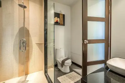 a bathroom with a toilet and a glass shower at VILLA BUTON Private Pool Nai Harn beach in Nai Harn Beach
