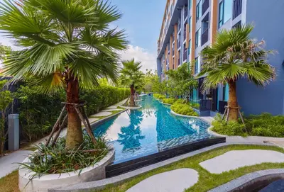 a swimming pool with palm trees next to a building at The Aristo by Holy Cow, 2-BR loft, 90 m2, pool view in Surin Beach