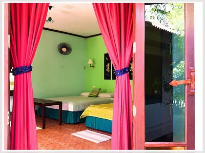 a bedroom with red curtains and a bed with a table at The Emerald Krabi Beach Resort in Klong Muang Beach