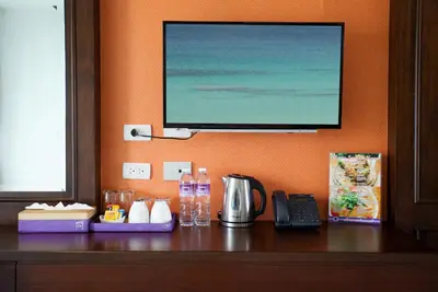 a flat screen tv hanging on a wall above a desk at Supicha Pool Access Hotel - SHA Plus in Phuket Town