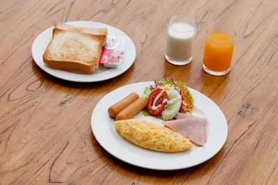 two plates of food on a table with two glasses of orange juice at Supicha Pool Access Hotel - SHA Plus in Phuket Town