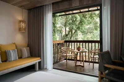 a room with a balcony with a table and a bench at Dinso Resort & Villas Phuket, Vignette Collection by IHG in Patong Beach