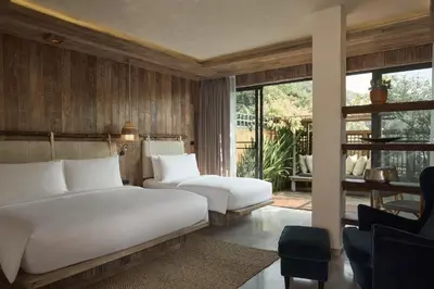 a bedroom with a large white bed and a chair at Dinso Resort & Villas Phuket, Vignette Collection by IHG in Patong Beach