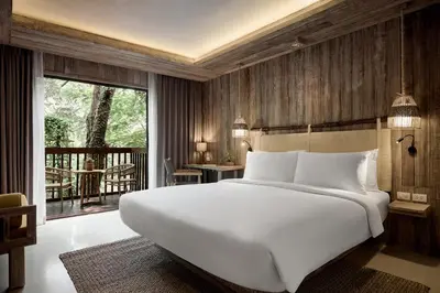 a bedroom with a large white bed and a balcony at Dinso Resort & Villas Phuket, Vignette Collection by IHG in Patong Beach