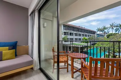 a room with a balcony with a bed and a table at DoubleTree by Hilton Phuket Banthai Resort in Patong Beach