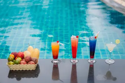 four cocktails and a basket of fruit next to a swimming pool at Blue Tara Hotel Krabi Ao Nang in Ao Nang Beach