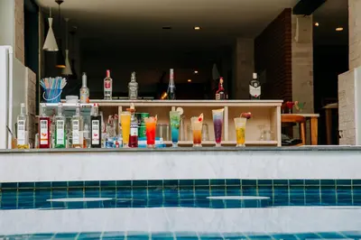 a bar behind a swimming pool with drinks at Blue Tara Hotel Krabi Ao Nang in Ao Nang Beach