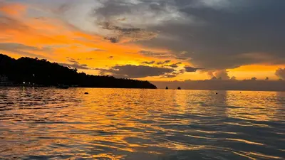 a sunset over a large body of water at Andaman Seaside Resort Bangtao Beach in Bang Tao Beach