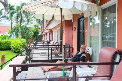 a man sitting on a table under an umbrella at Andaman Seaside Resort Bangtao Beach in Bang Tao Beach