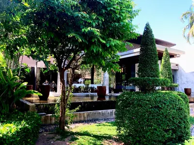 a garden with trees and bushes in front of a house at Malisa Villa Suites - SHA Extra Plus in Kata Beach