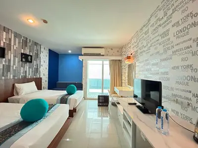a hotel room with two beds and a flat screen tv at Benyada Lodge - Surin Beach in Surin Beach