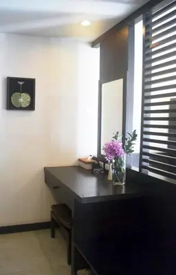 a desk in a room with a mirror and flowers at Benyada Lodge - Surin Beach in Surin Beach