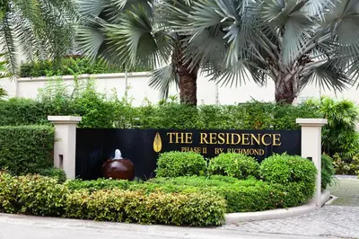 a sign for theresurance trust byrd in front of palm trees at The Residence Resort in Bang Tao Beach
