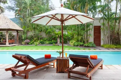 a pair of chairs and an umbrella next to a swimming pool at The Residence Resort in Bang Tao Beach