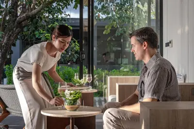 a man and a woman sitting at a table with wine glasses at Aleenta Phuket - Phang Nga - The Leading Hotels of the World in Natai Beach