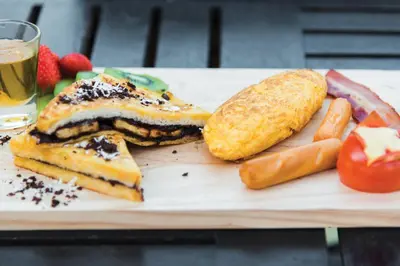 a plate of food with sandwiches and a drink at Woraburi Phuket Resort & Spa - SHA Plus in Karon Beach