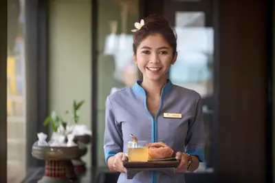 a woman holding a plate of food and a drink at Woraburi Phuket Resort & Spa - SHA Plus in Karon Beach