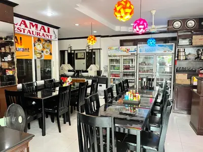 a restaurant with tables and chairs in a room at Lamai Apartment in Patong Beach