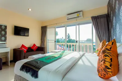 a bedroom with a large bed and a large window at Surin Sunset Hotel - SHA in Surin Beach