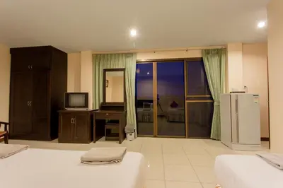 a room with two beds and a desk with a television at Surin Sunset Hotel - SHA in Surin Beach