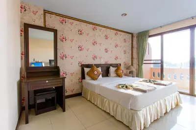 a bedroom with a bed with a mirror and a table at Surin Sunset Hotel - SHA in Surin Beach