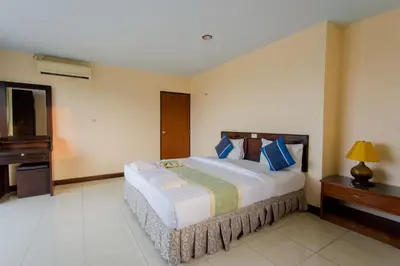 a bedroom with a large bed with blue pillows at Surin Sunset Hotel - SHA in Surin Beach