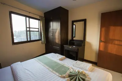 a bedroom with a bed with a dresser and a window at Surin Sunset Hotel - SHA in Surin Beach