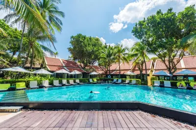 a swimming pool at a resort with palm trees at Impiana Beachfront Resort Patong, Phuket in Patong Beach