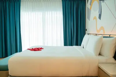 a white bed with a red flower on top of it at M Social Hotel Phuket in Patong Beach