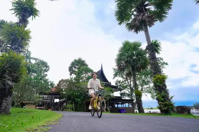 a man riding a bike down a road with palm trees at The Hotspring Beach Resort & Spa - SHA Extra Plus in Natai Beach