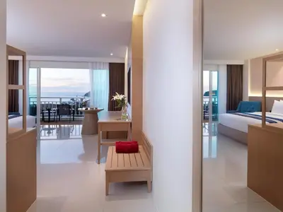 a hotel room with a bedroom and a bed at Chanalai Flora Resort, Kata Beach in Kata Beach