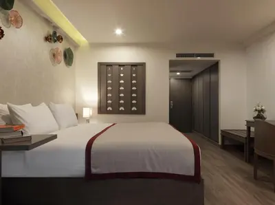 a bedroom with a large white bed and a desk at Chanalai Flora Resort, Kata Beach in Kata Beach