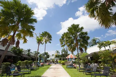 a park with palm trees and chairs and a sidewalk at Access Resort & Villas - SHA Plus in Karon Beach
