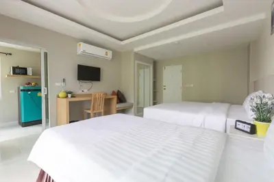 a bedroom with two beds and a desk and a tv at The Royal P Phuket - SHA Plus in Phuket Town