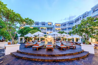 a patio with lounge chairs and umbrellas in front of a building at Andaman Seaview, Karon Beach - SHA Plus in Karon Beach