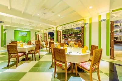 a restaurant with tables and chairs and green walls at Andaman Seaview, Karon Beach - SHA Plus in Karon Beach