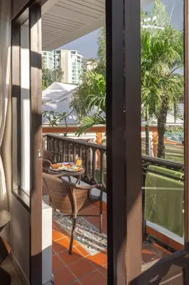 a room with a balcony with a table and chairs at The Pe La Resort, Phuket - SHA Extra Plus in Kamala Beach