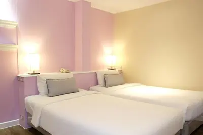 two beds in a room with two lamps on the wall at The Beach Boutique House in Kata Beach