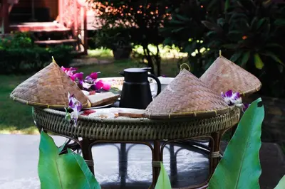 a wicker chair with a table and flowers on it at Cocco House in Ao Nang Beach