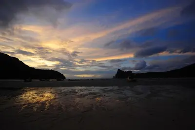 a sunset on a beach with a cloudy sky at Phi Phi Twin Palms Bungalow in Phi Phi Don