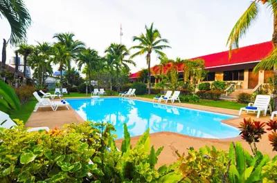 a swimming pool in front of a house with palm trees at The Golddiggers Resort in Nai Yang Beach