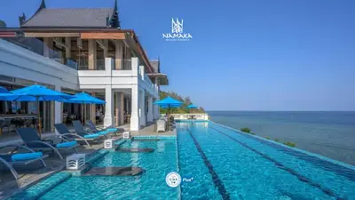 a swimming pool with chairs and umbrellas next to a building at Namaka Resort Kamala in Kamala Beach
