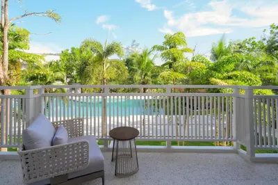 a chair and stool on a balcony with a view of the water at Centara Karon Resort Phuket in Karon Beach